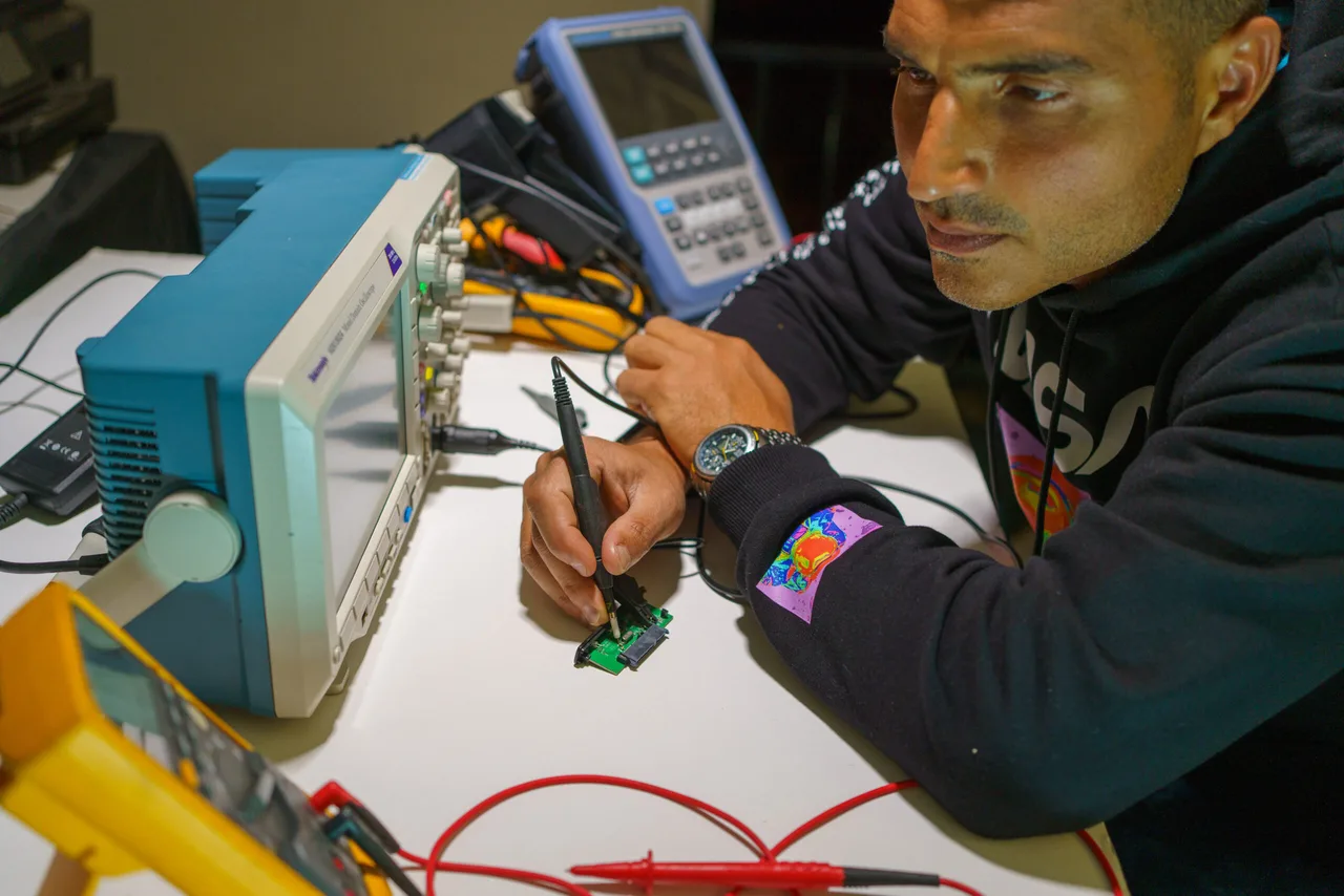 Loay Elbasyouni developing electronic hardware at a laboratory bench with an oscilloscope.