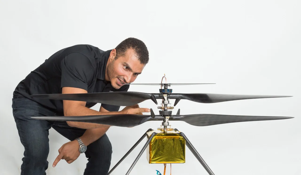 Loay Elbasyouni examining Mars helicopter hardware with its rotor blades extended.